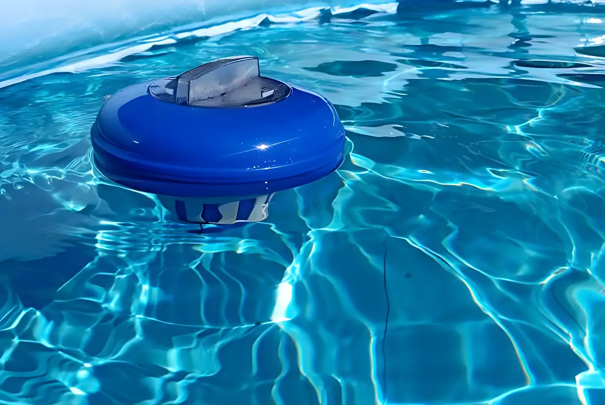 Close-up of a blue and white floating chlorine dispenser bobbing in bright, rippling swimming pool water for sanitization