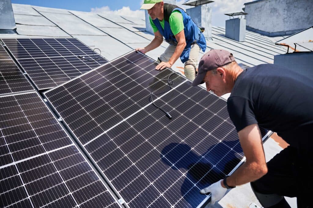 Two professional installers carefully mounting high-efficiency solar panels on a residential rooftop, providing renewable energy services in Ocala, FL.