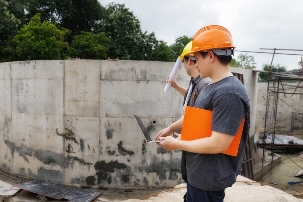 A Florida DBPR certified pool contractor reviewing project plans on a laptop at a residential pool construction site in Jacksonville, FL.