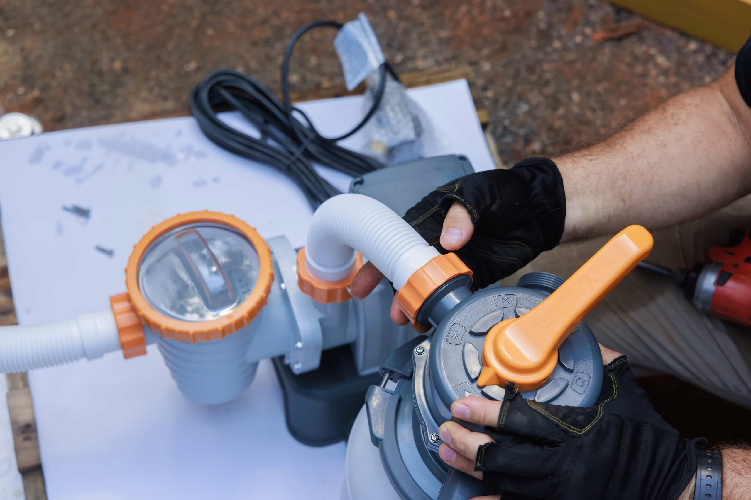Close-Up Of A Technician&Amp;Apos;S Hands Wearing Black And Yellow Gloves Assembling Grey And Orange Hoses On A Pool Filter System, Demonstrating Professional Variable-Speed Pool Pump Upgrades In Phoenix, Az.